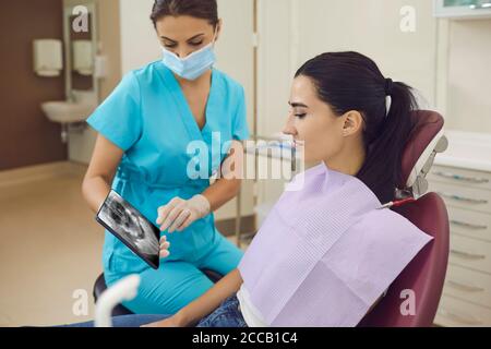 Dentista che mostra la vista panoramica dei denti a raggi X per la paziente Foto Stock