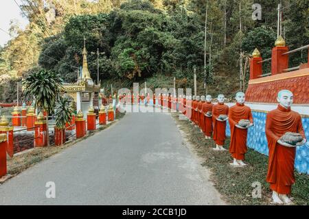 Fila di statue di monaci buddisti vicino ad un popolare ingresso turistico e grotta religiosa vicino alla città di hPa-an, Myanmar. Viaggi paesaggi e. Foto Stock