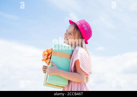 Grazie per l'acquisto. Gioiosa femmina bambino che tiene confezione regalo-confezionata. Regalo in mano. Sorridente bambina con regalo di shopping. Vendita del Black Friday. Concetto di festa. Giorno internazionale dei bambini. Foto Stock