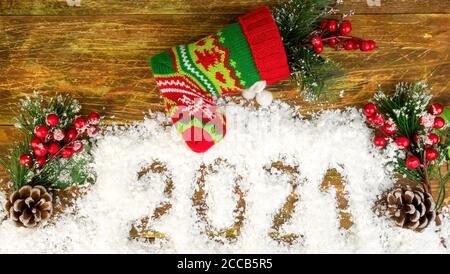 Rami di Natale con bacche e coni in neve decorativa, che dice 2021 e maglia Natale calza o Santas stivale. Concetto di umore di Natale. T Foto Stock