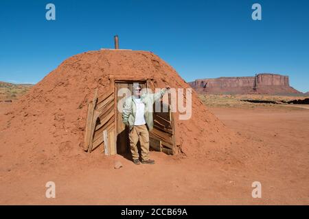 Una guida turistica Navajo si trova di fronte all'hogan in cui è cresciuto, Monument Valley, Utah, USA Foto Stock