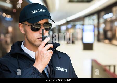 Guardia di sicurezza che usa Walkie Talkie nel centro commerciale Foto Stock