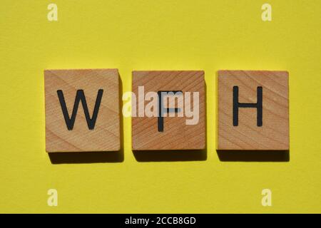 WFH, acronimo di Work Form Home, in lettere alfabetiche in legno isolate su sfondo giallo Foto Stock