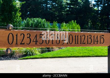 Tabellone segnapunti per palline. Tabellone segnapunti per bocce. Numeri neri su tavola di legno marrone. Verde esterno paesaggio sfondo. Foto Stock