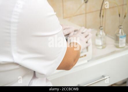 Primo piano della mano di un infermiere preparazione di fiale mediche per l'iniezione in un ufficio medico, vista posteriore, fuoco selettivo. Foto Stock