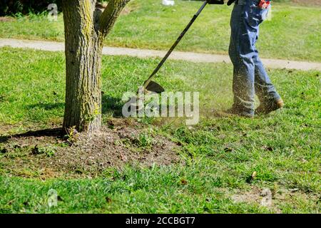 Chiudere la mano dell'uomo utilizzando il rasaerba che taglia l'erba su fuoco selettivo verde a portata di mano Foto Stock