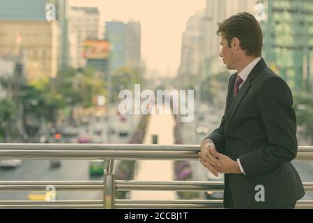 Imprenditore guardando le strade e le riflessioni sulla passerella a Bangkok City Foto Stock