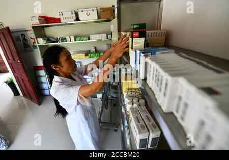 (200821) -- LONGLI, 21 agosto 2020 (Xinhua) -- Luo Mu sceglie medicinali per gli abitanti del villaggio presso la clinica nel villaggio di Cuiwei nella contea di Longli, nella prefettura autonoma di Qiannan Buyi-Miao, nella provincia sudoccidentale di Guizhou, 18 agosto 2020. Luo Mu, 49 anni, medico del gruppo etnico Buyi, lavora nel villaggio di Cuiwei, nella contea di Longli. Laureata in una scuola di medicina nel 2004, tornò al villaggio servendo da medica. Ha convertito il proprio salotto in una clinica con l'apparecchiatura medica che aveva acquistato, per trattare i pazienti nel villaggio. Nel 2007, Luo è stato impiegato in una clinica appena fondata nel vaso Foto Stock