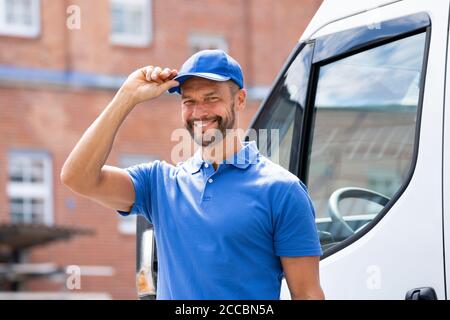 Smiling Delivery uomo o Handycam in uniforme vicino al camion Foto Stock