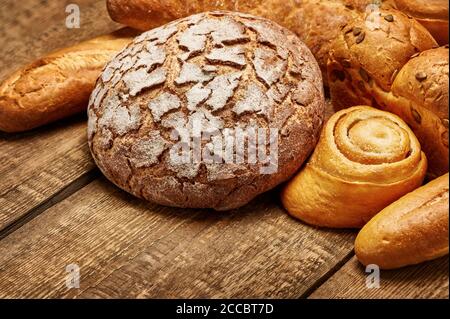 Assortimento di pane su tavola rustica in legno. Pane vario. Scatto in studio. Vita morta. Foto Stock