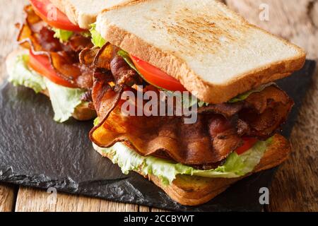 Popolari panini blt americano con pancetta croccante, insalata fresca e pomodori primo piano su una tavola di ardesia sul tavolo. Orizzontale Foto Stock
