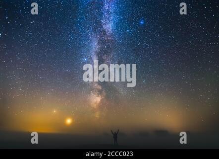 Paesaggio con la galassia Via Lattea e l'uomo in piedi contro le stelle, concetto di libertà Foto Stock