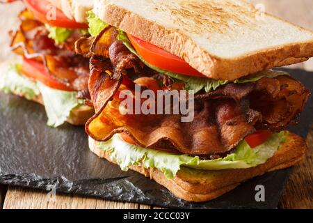 panino blt con pancetta croccante, insalata fresca di iceberg e pomodori primo piano su una tavola di ardesia sul tavolo. orizzontale Foto Stock