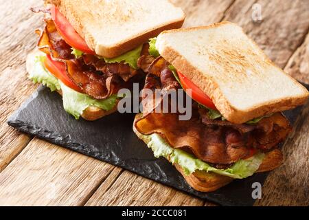 Delizioso panino blt con pancetta, insalata di iceberg e pomodori primo piano su una tavola di ardesia sul tavolo. Orizzontale Foto Stock