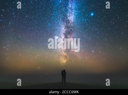 Paesaggio con la galassia Via Lattea e coppia in piedi contro le stelle, concetto di libertà Foto Stock