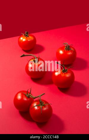 Pomodori freschi presentati su sfondo rosso, creativo minimalismo concetto Foto Stock