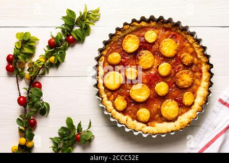 Torta aperta di pasta frolla con prugna di ciliegia, clafoutis di prugna mirobalana su sfondo bianco Foto Stock