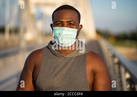 Ritratto di giovane afroamericano con maschera protettiva sul viso. Comportamento responsabile pandemico del virus corona. Foto Stock