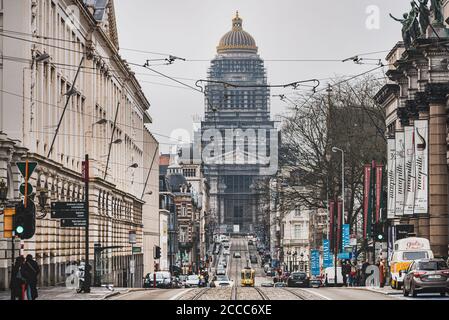 La trafficata strada di Rue de la Regence con un tram sulla strada. Alla fine della strada si trova l'imponente Palazzo di Giustizia o il Tribunale di Bruxelles Foto Stock