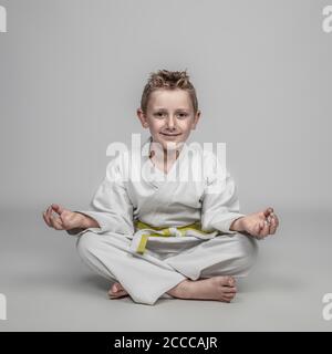 ritratto di un bambino che indossa kimono arti marziali seduto una posizione meditativa Foto Stock