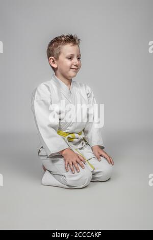 Bambino che pratica il karate in posizione seduta in stile giapponese. studio ritratto Foto Stock