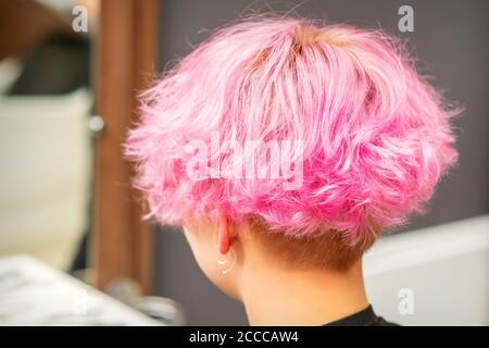 Vista posteriore della pettinatura rosa della giovane donna dopo la tintura capelli e di fare i punti di forza nel salone di bellezza Foto Stock