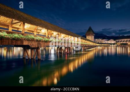 Ponte della Cappella illuminato al crepuscolo. Famoso punto di riferimento contro il Monte Pilatus a Lucerna, Svizzera. Foto Stock