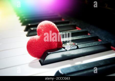 concetto di relazione romantica : cuore rosso velluto e anello di diamante lucido sul pianoforte Foto Stock
