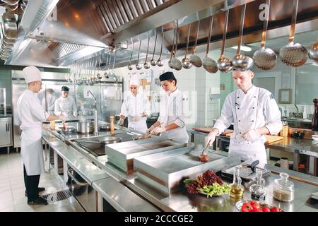 Cucina moderna. I cuochi preparano pasti sul fornello nella cucina del ristorante o albergo. Il fuoco in cucina Foto Stock