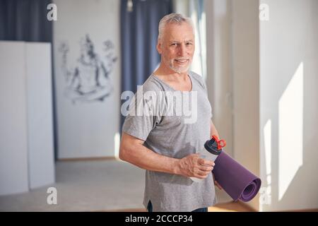 Un uomo che tiene una bottiglia d'acqua in perfetta forma Foto Stock