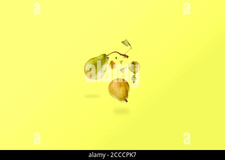 Pere fresche che si innalzano nell'aria con un'ombra su uno sfondo giallo. Concetto di abbondanza di frutta. Modello Foto Stock