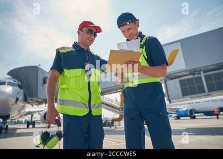 Uomini in abbigliamento da lavoro in piedi in un aeroporto Foto Stock