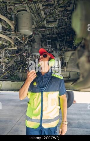 Meccanico dell'aviazione qualificato che ispeziona il fondo dell'aeroplano Foto Stock