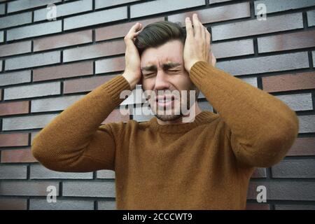 L'uomo sensazione emozioni dolorose, urlando, testimoniando la morte del caro amico, essendo miserabili e devastato, tenendo le palme sulla testa, urla di dolore un Foto Stock
