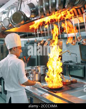 Cucina moderna. I cuochi preparano pasti sul fornello nella cucina del ristorante o albergo. Il fuoco in cucina. Foto Stock