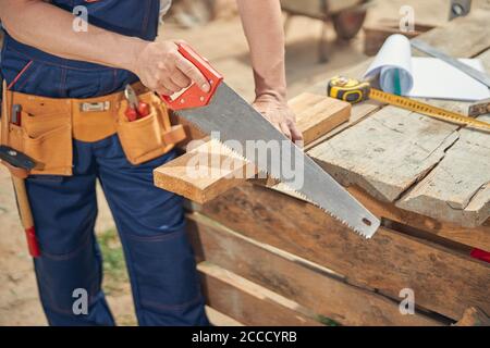 Falegname che sega un pezzo di barra di legno Foto Stock