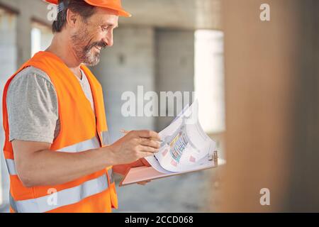 Uomo in un gilet riflettente che esamina i suoi progetti Foto Stock