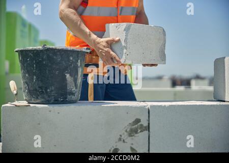 Mani maschili forti che tengono un mattone bianco Foto Stock