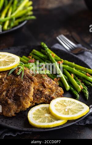 Filetti di pesce di tilapia al forno con fette di limone e asparagi una piastra nera Foto Stock