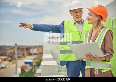 Lavoratore maschile in occhiali che mostra qualcosa ad un appaltatore Foto Stock