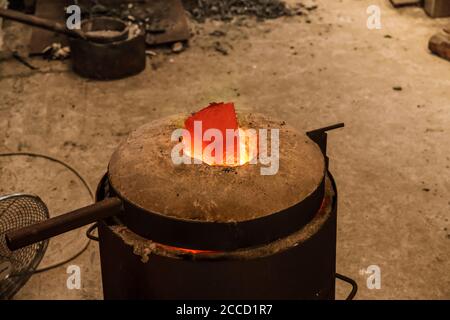 Fusione del bronzo in piccola fonderia. La sequenza di immagini mostra il processo di fusione completo, dalla fusione di lingotti alla rottura del guscio ceramico di una scultura. Foto Stock