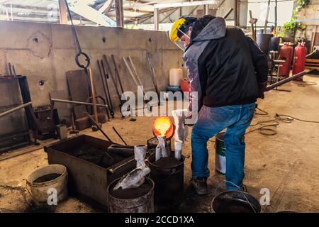 Fusione del bronzo in piccola fonderia. La sequenza di immagini mostra il processo di fusione completo, dalla fusione di lingotti alla rottura del guscio ceramico di una scultura. Foto Stock