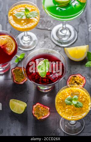 Assortimento di cocktail diversi con frutta fresca, ghiaccio e menta su sfondo nero. Foto Stock