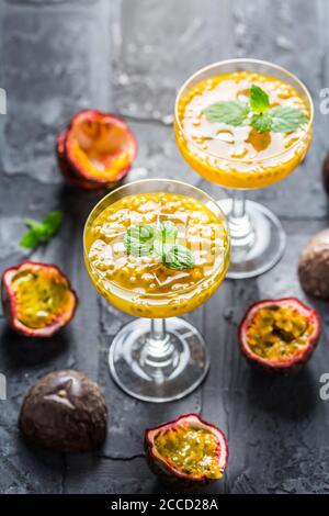 Cocktail alcolico o non alcolico con frutta fresca di passione (maracuya) e menta su sfondo nero. Foto Stock