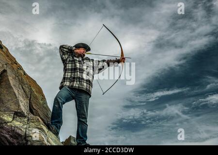 Cacciatore ricreativo in cappello tiro longbow. Tiro naturale di tiro con l'arco. Foto Stock