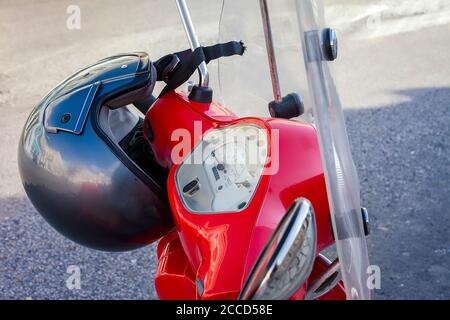 Scooter rosso. Isolato, primo piano della moto rossa con casco appeso sulla barra cromata. Immagine stock. Foto Stock