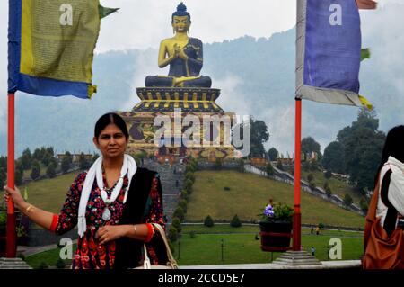 Una Signora Indiana in posa per una foto di fronte alla Statua del Buddha del Parco Ravangla di Sikkim, messa a fuoco selettiva Foto Stock