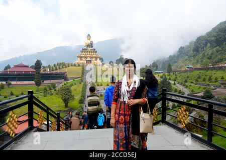 Una Signora Indiana in posa per una foto di fronte alla Statua del Buddha del Parco Ravangla di Sikkim, messa a fuoco selettiva Foto Stock