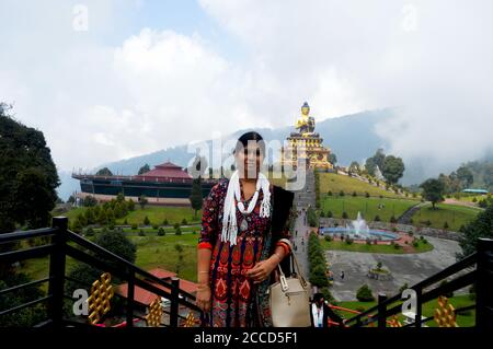 Una Signora Indiana in posa per una foto di fronte alla Statua del Buddha del Parco Ravangla di Sikkim, messa a fuoco selettiva Foto Stock