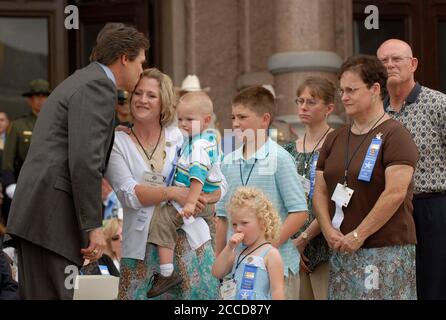 Austin, TX 7 maggio 2007: Il governatore del Texas Rick Perry (l) bacia Christy Carty, vedova del Texas Department of Public Safety Trooper Jimmy Ray Carty, Jr., in un servizio commemorativo presso il Campidoglio del Texas per i 25 ufficiali di pace del Texas uccisi nella linea di servizio negli ultimi due anni. ©Bob Daemmrich Foto Stock